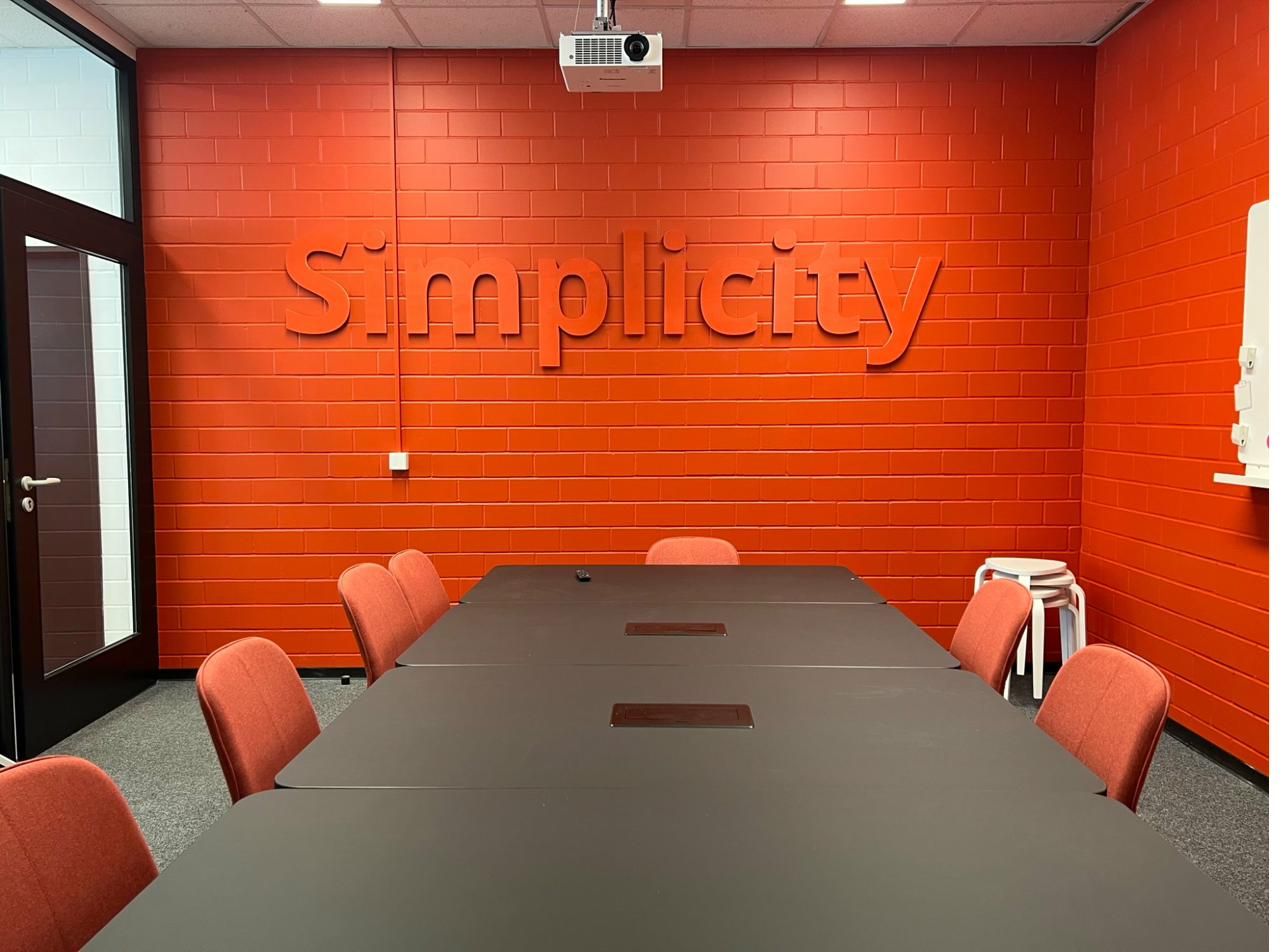 Konferenzraum mit Simplicity-Schriftzug an der Wand