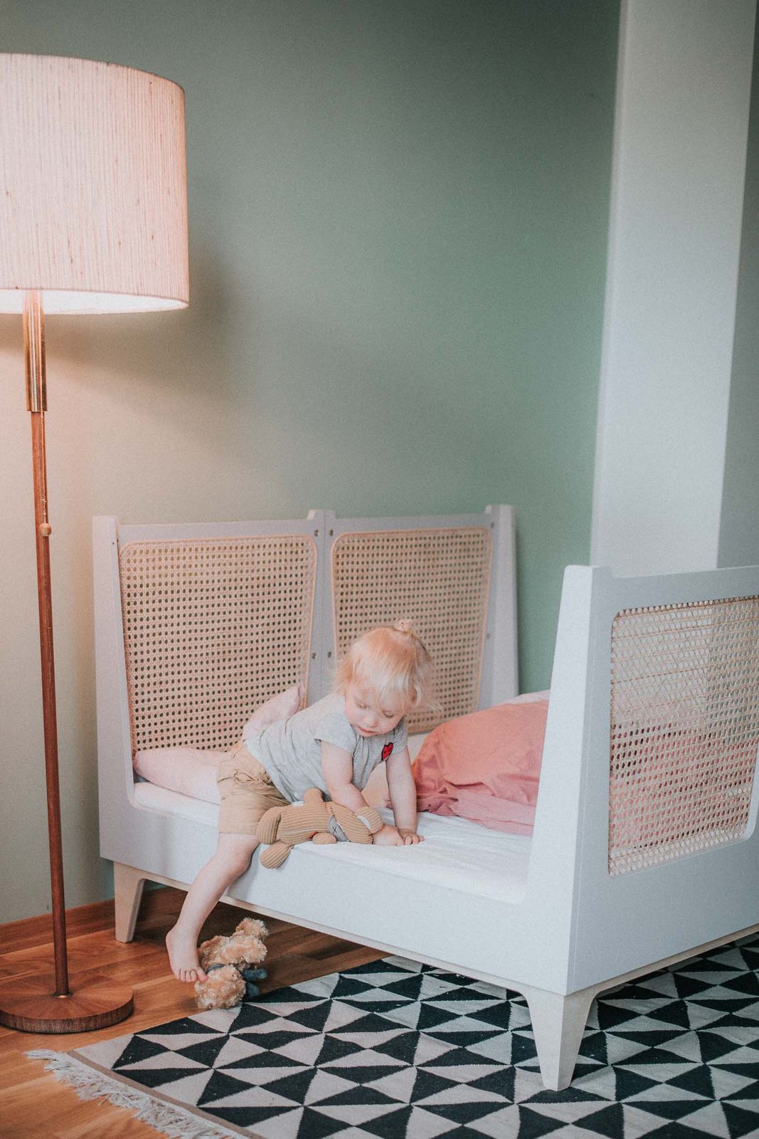 Kind liegt zufrieden im Kinderbett, Kopf auf dem Kissen, weiches Licht