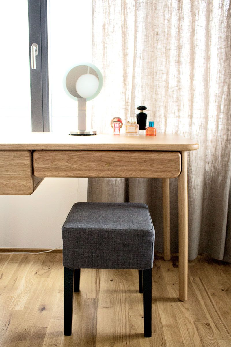 Schminktisch mit rundem Spiegel, dezenter Beleuchtung und sorgfältig arrangierten Accessoires